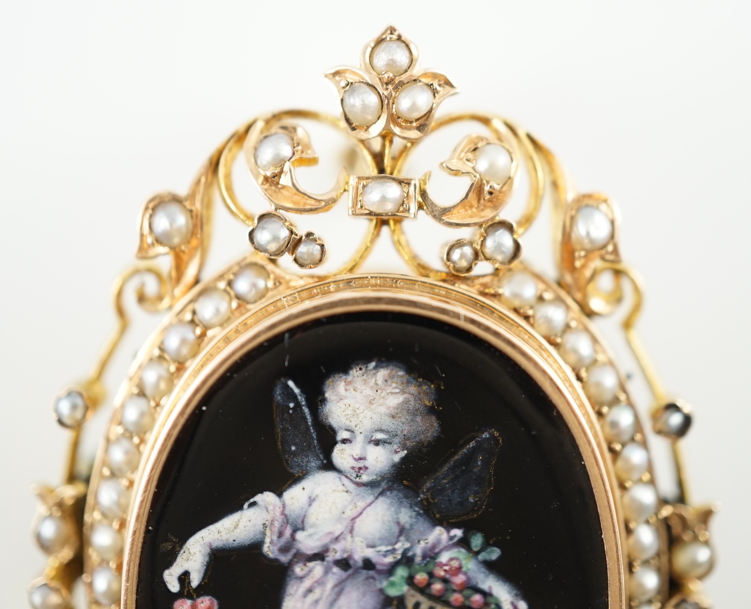 A Victorian oval gold and enamel pendant/brooch, painted with a cherub offering cherries to a dove, within a black and split pearl outer border